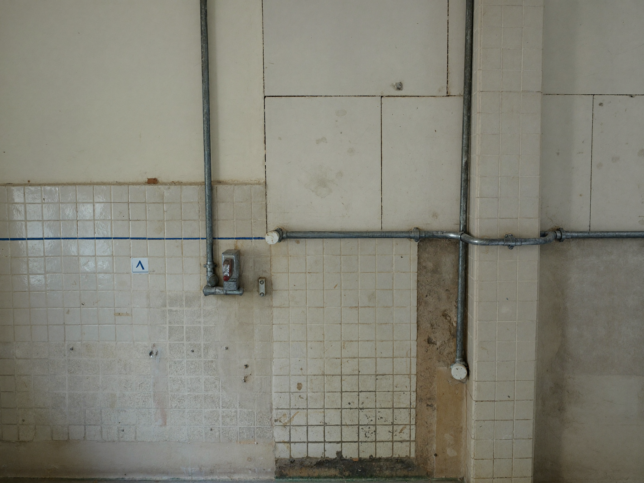 Leere Küchenwand mit freiliegenden Leitungen und Fliesenabdrücken