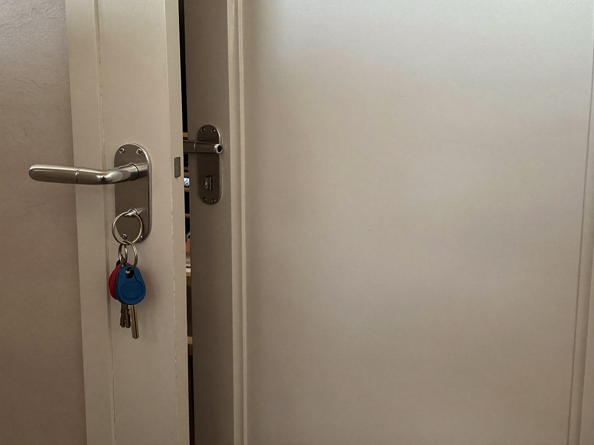 Angelehnte Wohnungstür mit steckendem Schlüssel