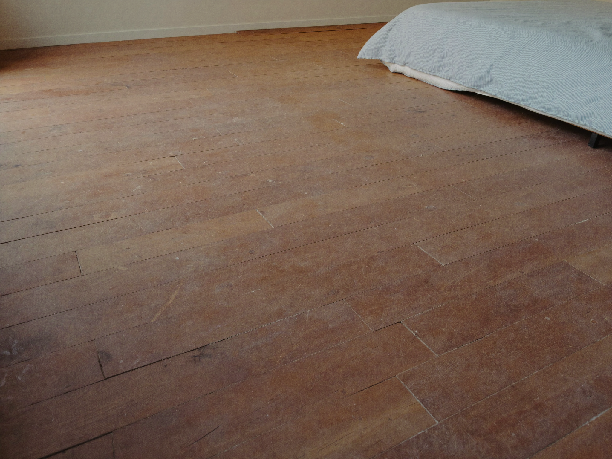 Leeres Schlafzimmer mit blanken Dielen nach dem Abbau des Betts