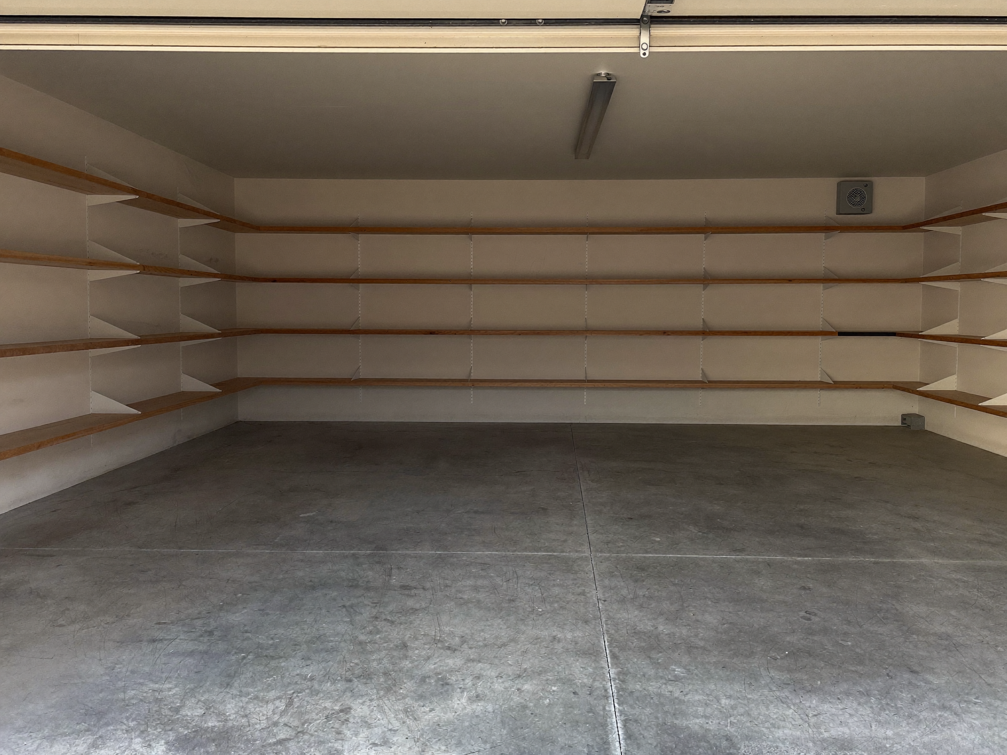 Leer geräumte Garage mit gekehrtem Betonboden und leeren Regalen